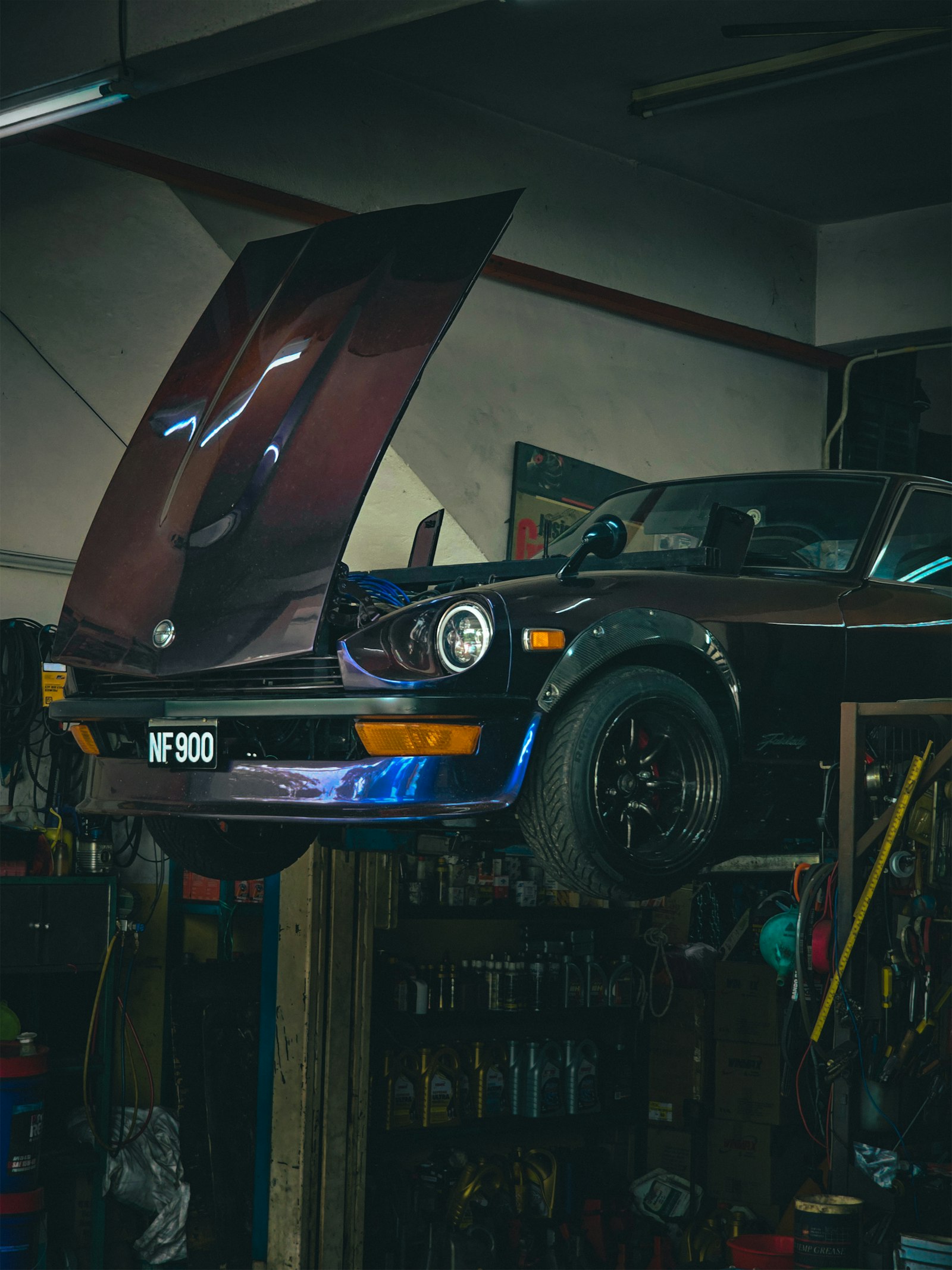 A car with its hood open inside a workshop bay.