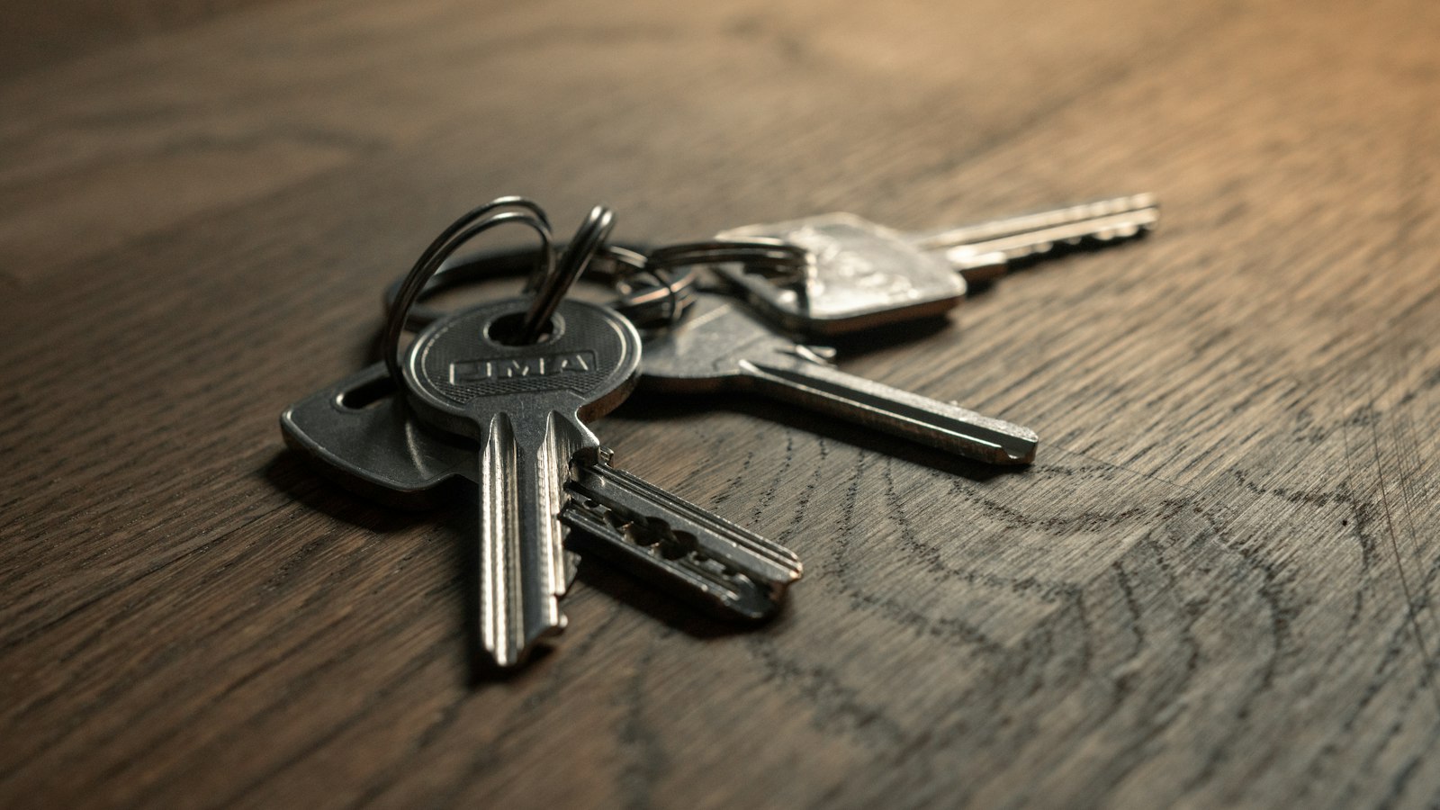 A single car key resting on folded vehicle paperwork on a wooden table.