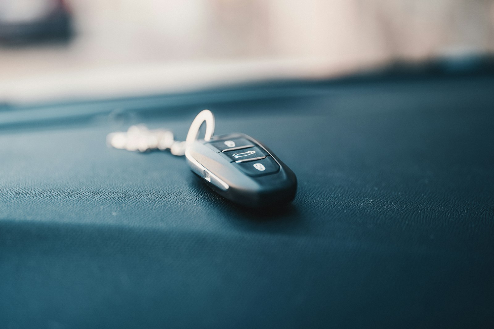 A car key fob resting on a dark seat inside a vehicle.