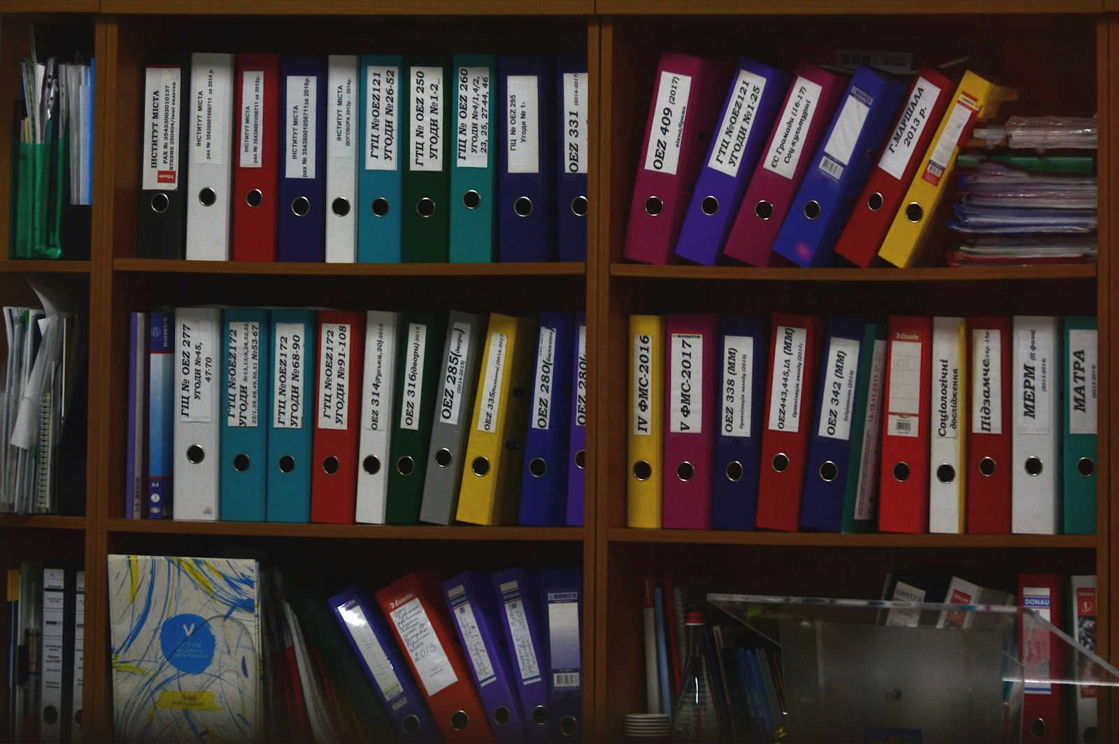 Shelves of labeled paper record folders in a quiet office records room.