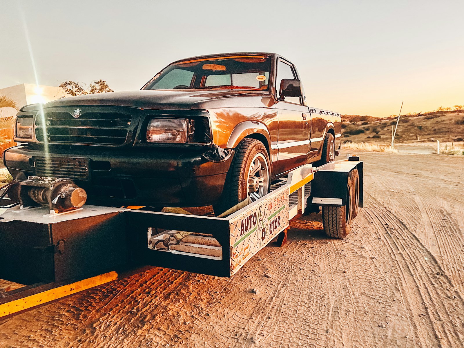 A pickup truck secured on a flatbed tow trailer.