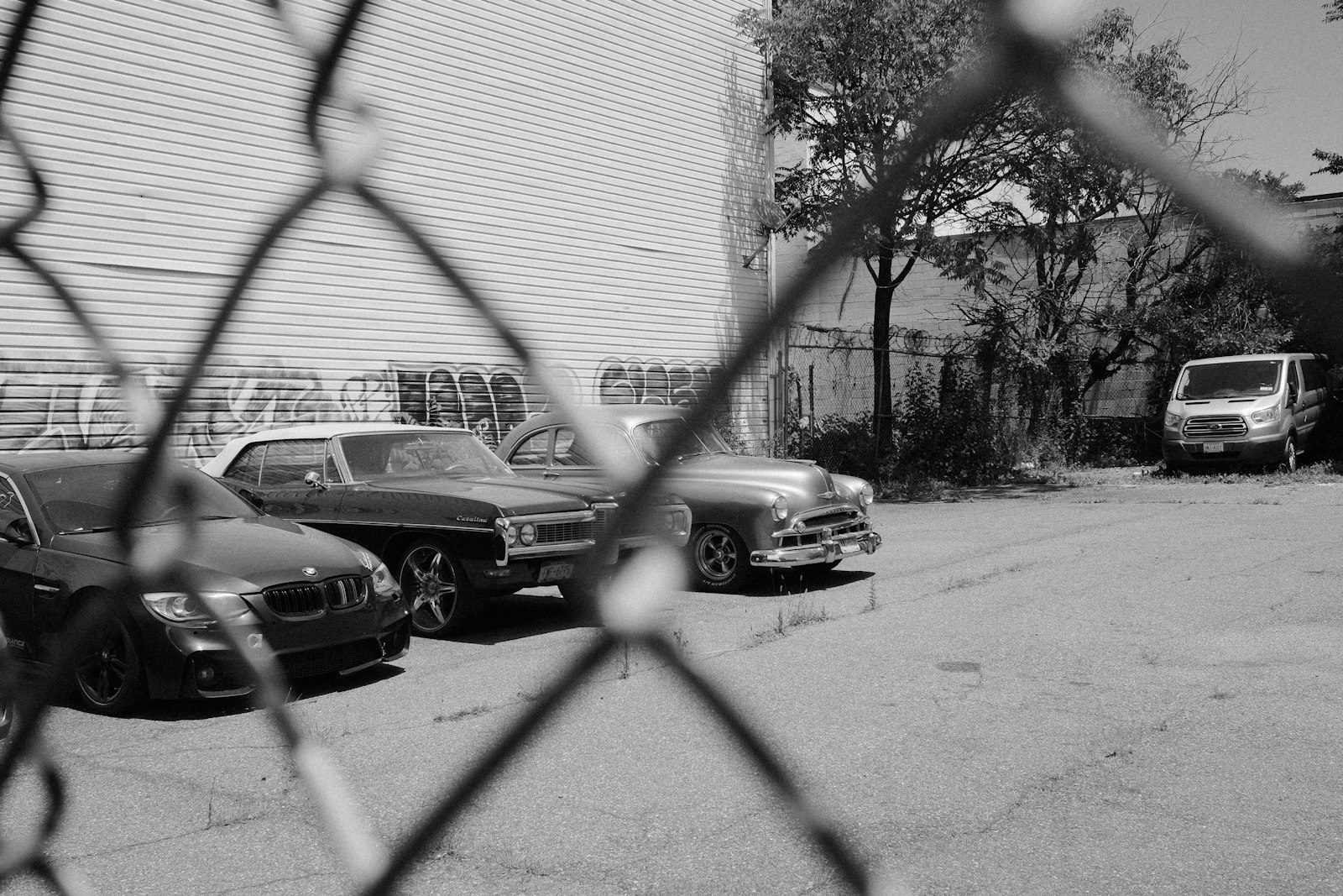 Rows of parked vehicles behind a tall chain link fence at a storage yard as the light fades.