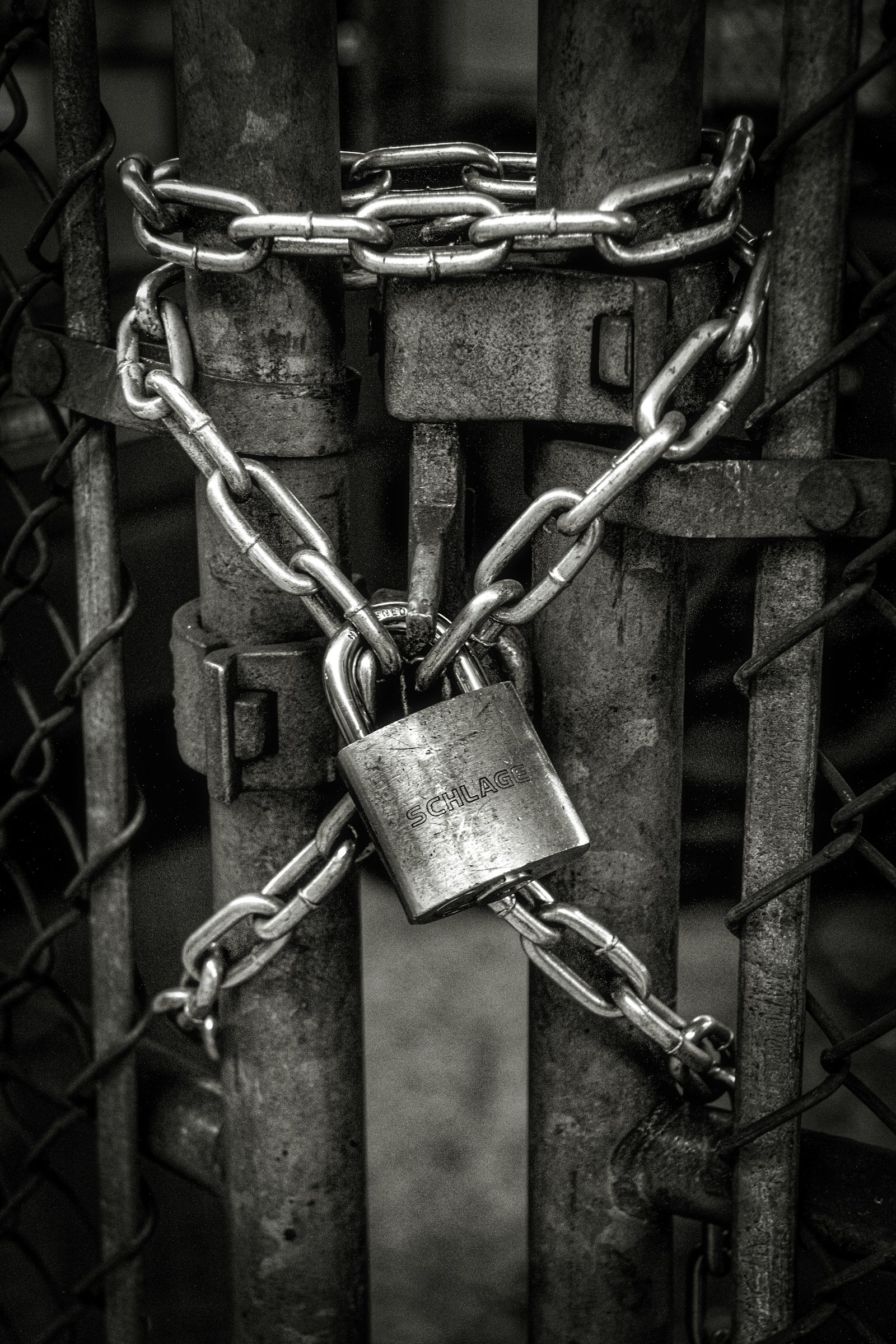 A heavy padlock and chain securing a closed industrial yard gate.